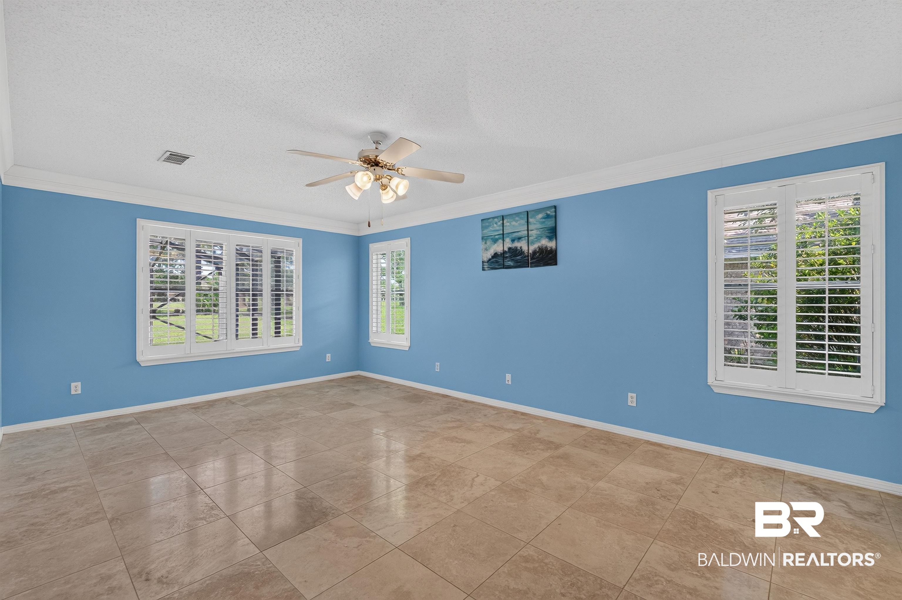 22685 County Road 12 Foley, AL 36535 - Photo 48 of 89 Spacious room featuring neutral tile flooring, multiple windows with white plantation shutters, crown molding, and a ceiling fan with integrated lighting