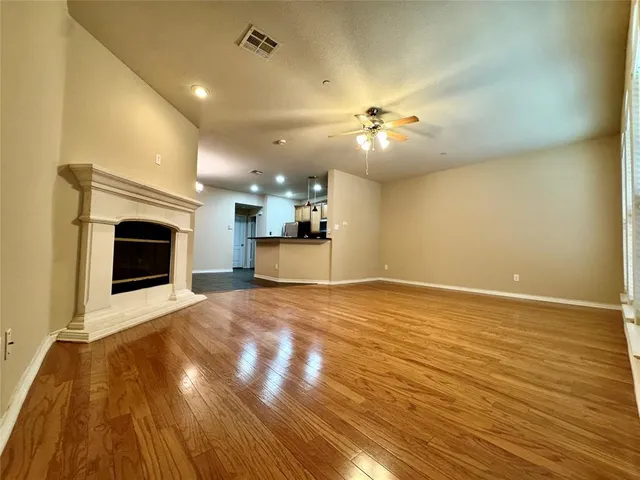 a view of an empty room with kitchen and a fireplace