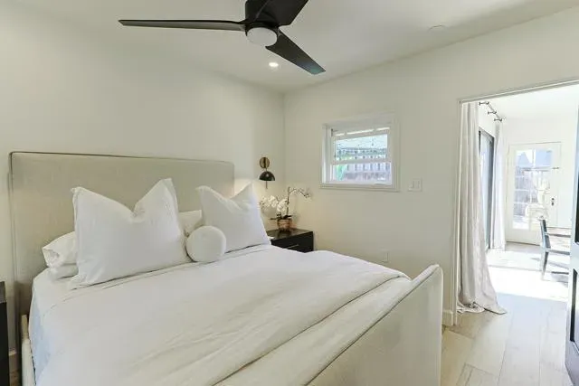 a spacious bedroom with a bed and a flat tv screen on dresser