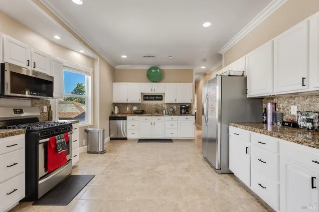 a kitchen with granite countertop a sink stainless steel appliances and white cabinets
