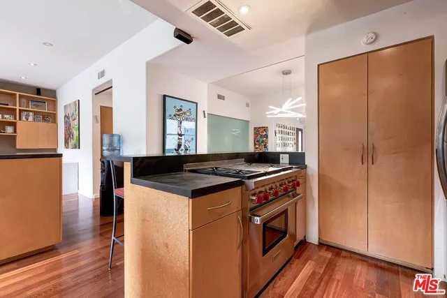 a kitchen with stainless steel appliances granite countertop a refrigerator a stove and a wooden floors