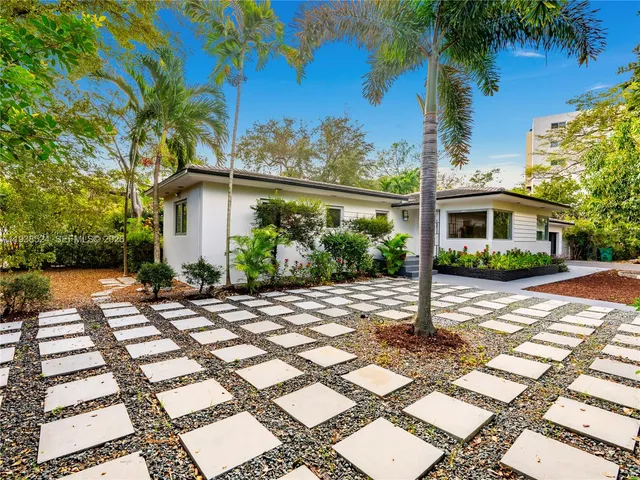 a front view of a house with a yard and potted plants