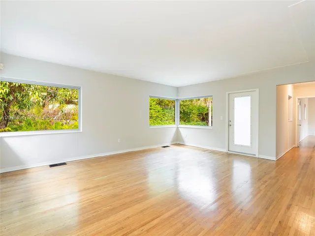 a view of an empty room with wooden floor and windows