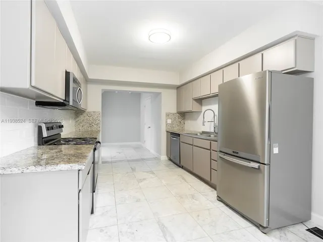 a kitchen with stainless steel appliances granite countertop a refrigerator a stove and a sink