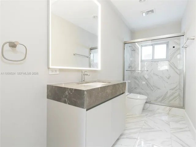 a bathroom with a sink a toilet and shower