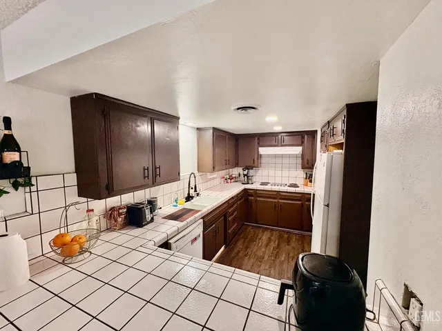 a large white kitchen with a sink and a refrigerator