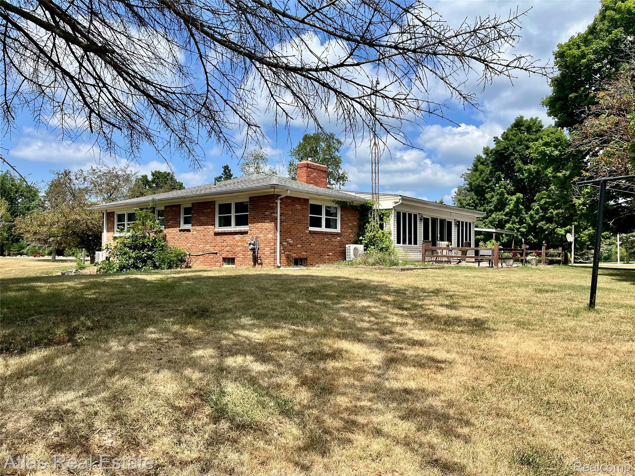 12026 Coolidge Road Goodrich, MI 48438 - Photo 7 of 56 Brick exterior residence featuring a sunroom, expansive yard, and mature trees