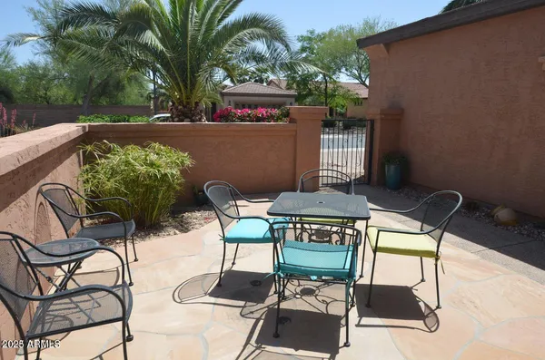 a patio with table and chairs and potted plants