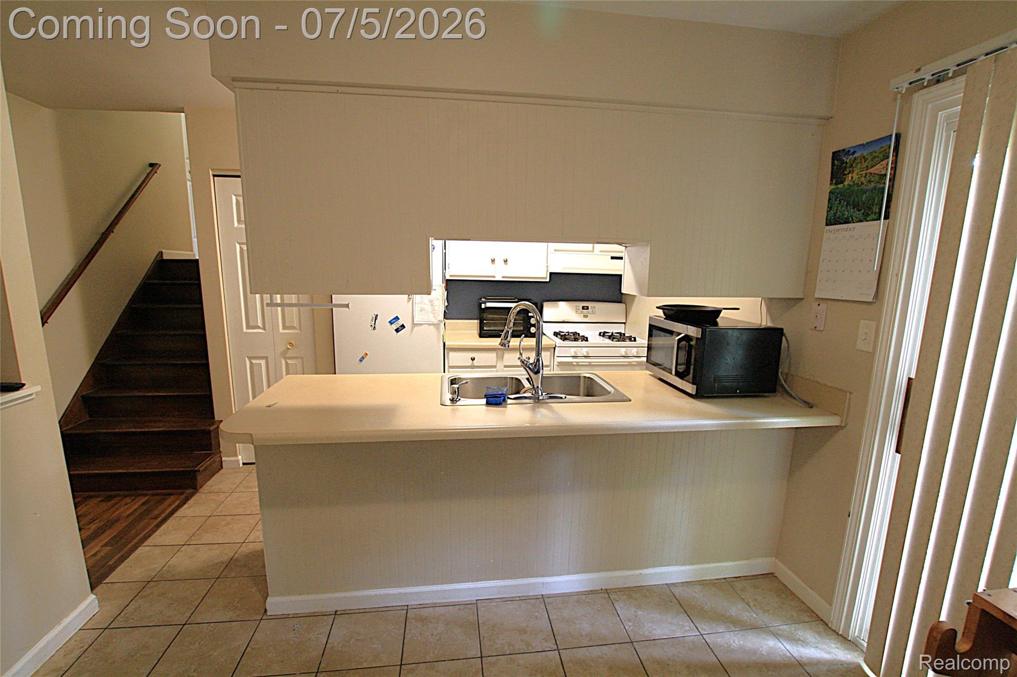 12403 Willard Road Montrose, MI 48457 - Photo 15 of 30 Kitchen with light countertops, a peninsula, white appliances, light tile patterned floors, and extractor fan