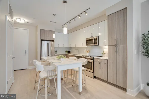 a kitchen with stainless steel appliances kitchen island a table chairs refrigerator and microwave