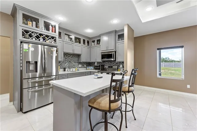 a kitchen with stainless steel appliances kitchen island granite countertop a refrigerator a stove a sink a dining table and chairs with wooden floor