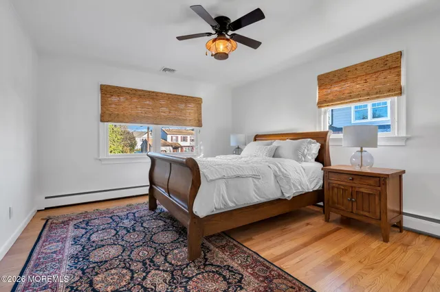 a bedroom with a bed and dresser with wooden floor