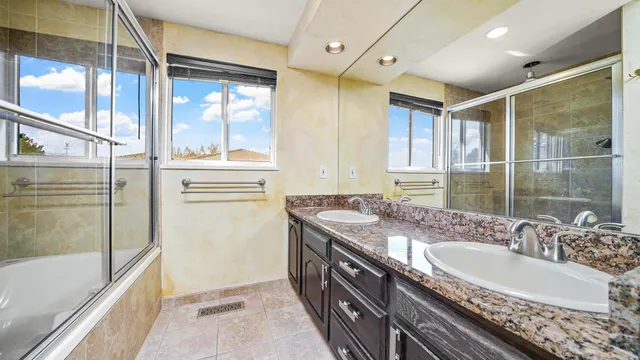 a bathroom with a granite countertop tub sink and mirror
