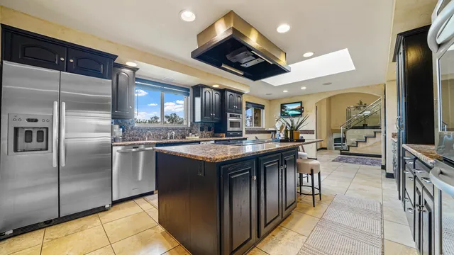 a kitchen with stainless steel appliances granite countertop a stove a sink and a refrigerator