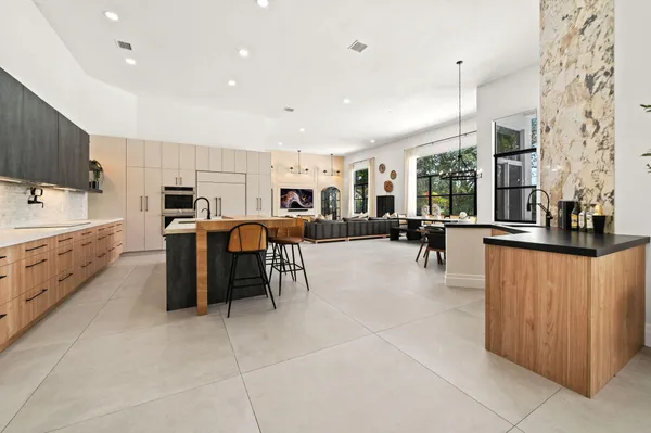 a large white kitchen with lots of counter space cabinets and stainless steel appliances