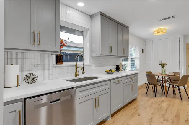 a kitchen with white cabinets and sink