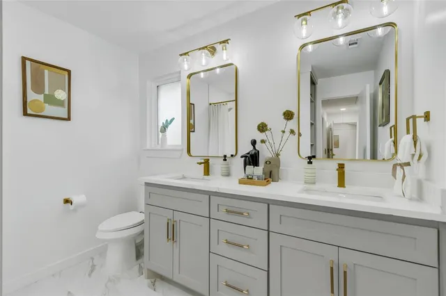 a bathroom with 2 sink toilet and a mirror