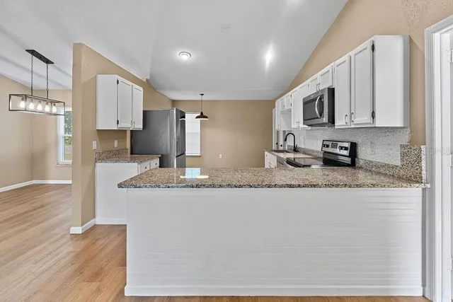 a kitchen with stainless steel appliances granite countertop a sink refrigerator and cabinets