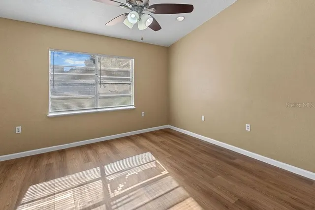 a view of an empty room with a window and wooden floor