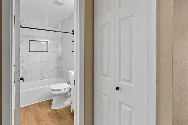 a view of an empty room with wooden floor and a window