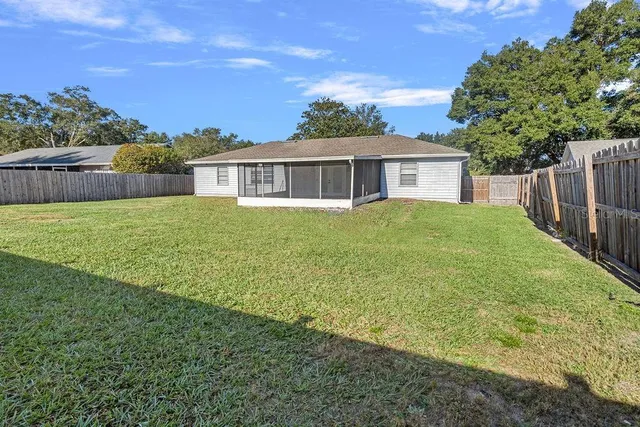 a view of a house with a yard and a large tree