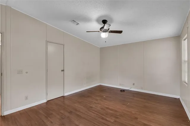 a view of an empty room with wooden floor and chandelier fan