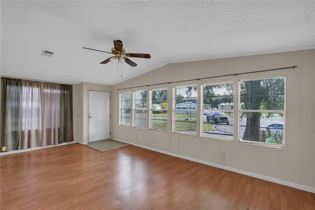 a view of empty room with wooden floor and fan