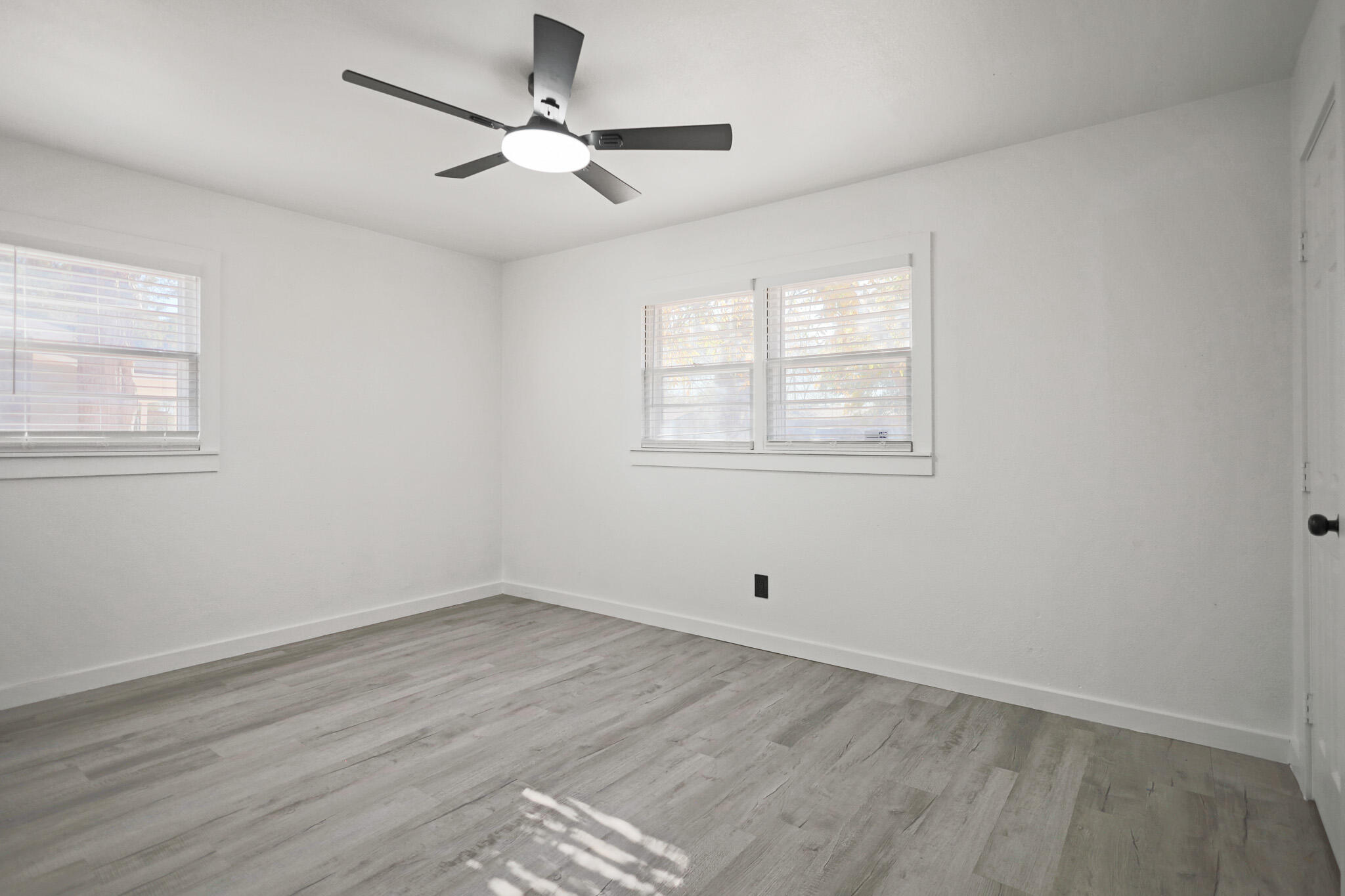 5512 45th Street Lubbock, TX 79414 - Photo 21 of 30 an empty room with wooden floor ceiling fan and windows