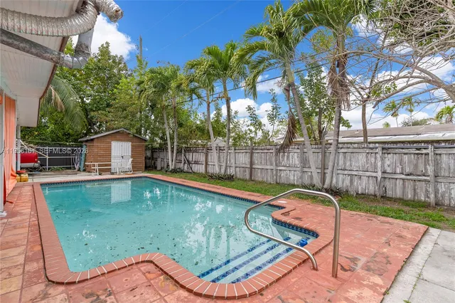 a view of a backyard with a small pool and wooden fence