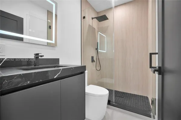 a bathroom with a granite countertop sink toilet and shower