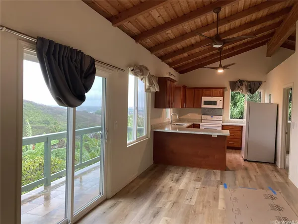 a kitchen with stainless steel appliances granite countertop a refrigerator a sink dishwasher a stove and a large window with wooden floor