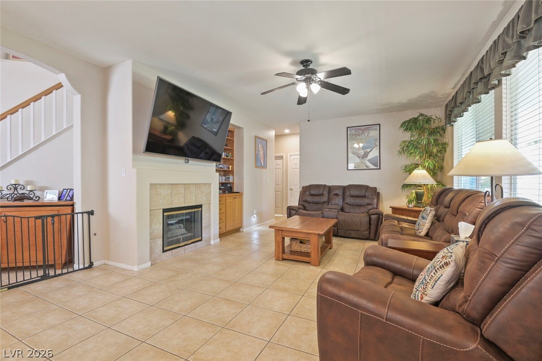 2356 Tilden Way Henderson, NV 89074 - Photo 8 of 30 A well-lit gathering space features a fireplace and staircase, with tiled flooring extending throughout.