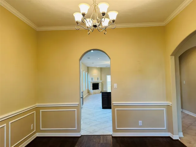 a view of a hallway with wooden floor and a chandelier