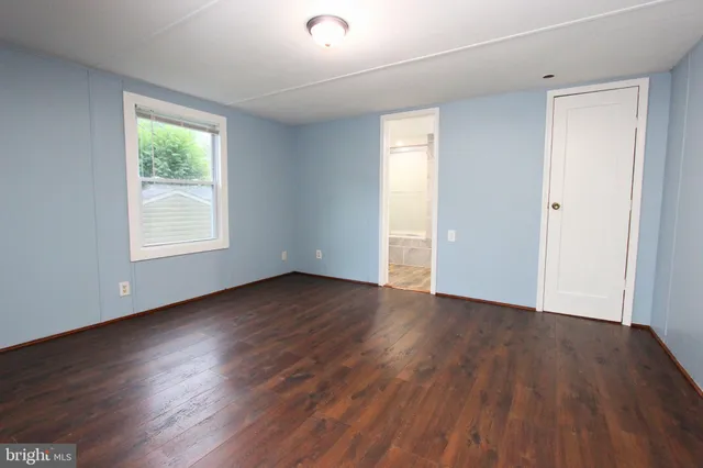 an empty room with wooden floor and window