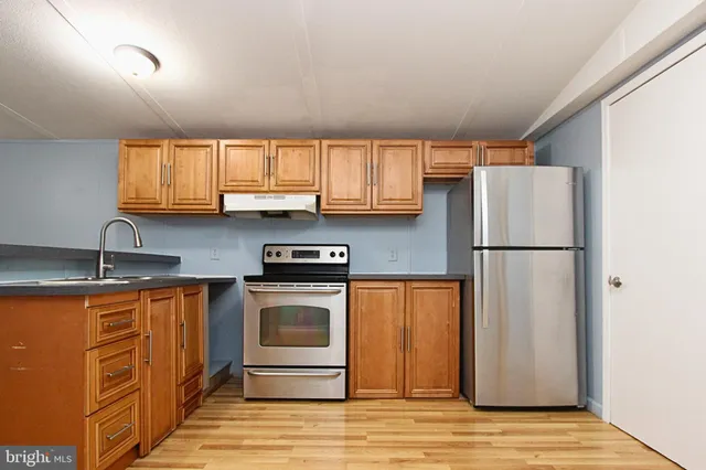 a kitchen with stainless steel appliances granite countertop a refrigerator a sink a stove a washer dryer and cabinets