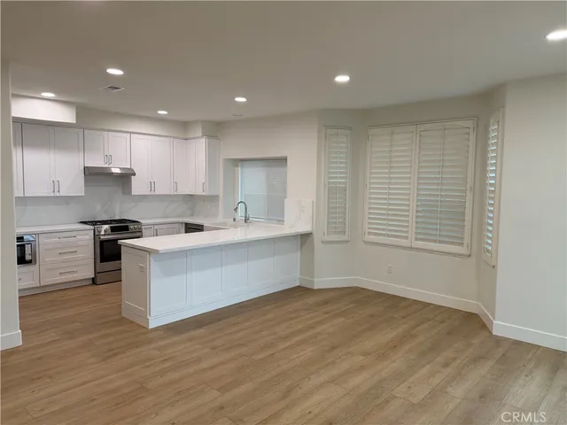 a large kitchen with kitchen island a sink wooden floor and a stove