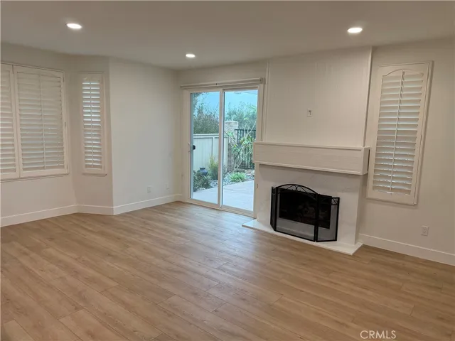 an empty room with wooden floor fireplace and windows