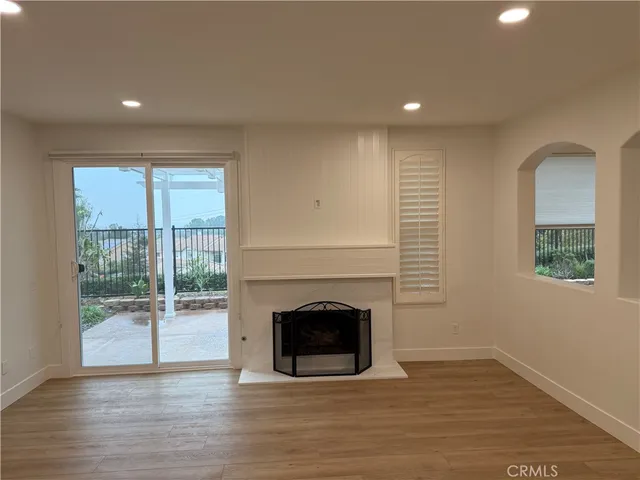 a view of empty room with wooden floor and fireplace