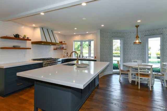 a kitchen with stainless steel appliances granite countertop a sink a stove and a wooden floors