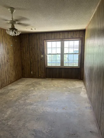 an empty room with a ceiling fan and window