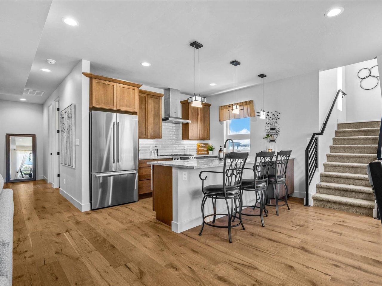 365 West Ridges Boulevard, Unit A Grand Junction, CO 81507 - Photo 12 of 42 a kitchen with stainless steel appliances kitchen island granite countertop a refrigerator a stove a microwave oven a dining table and chairs with wooden floor