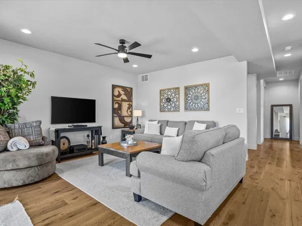 a kitchen with stainless steel appliances kitchen island granite countertop a refrigerator a stove a microwave oven a dining table and chairs with wooden floor
