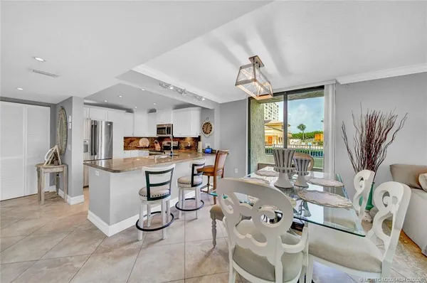 a very nice looking dining room with kitchen island furniture a large window and kitchen view