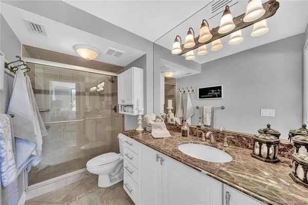 a bathroom with a granite countertop double vanity sink a mirror and a toilet