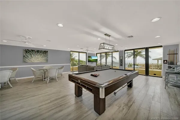 a room with furniture pool table wooden floor and windows