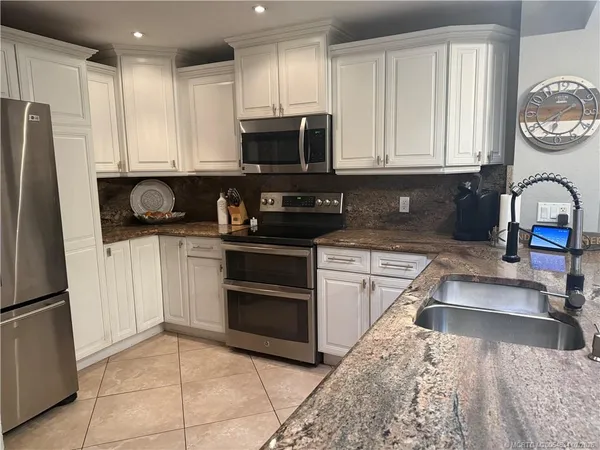 a kitchen with stainless steel appliances granite countertop a refrigerator sink and stove