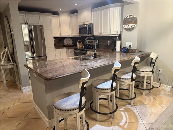 a kitchen with stainless steel appliances granite countertop a table chairs a refrigerator and microwave