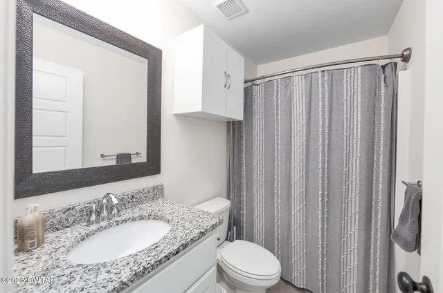a bathroom with a granite countertop sink toilet and shower