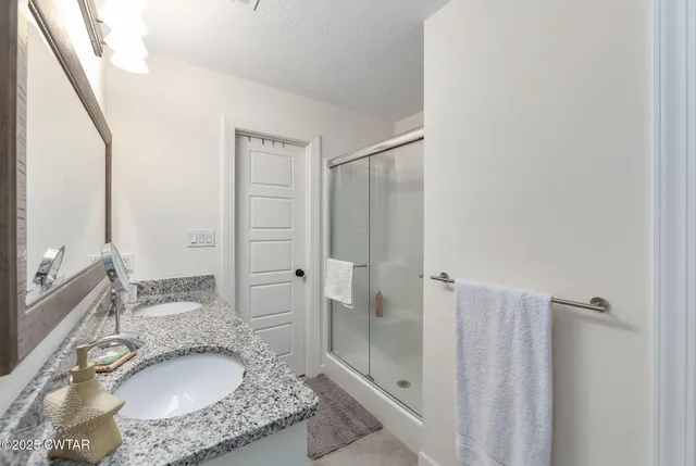 a en suite bathroom with a granite countertop sink and a mirror