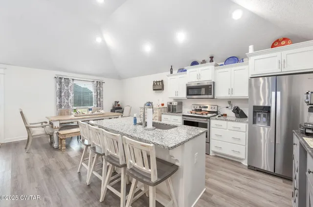 a kitchen with stainless steel appliances white cabinets and wooden floor